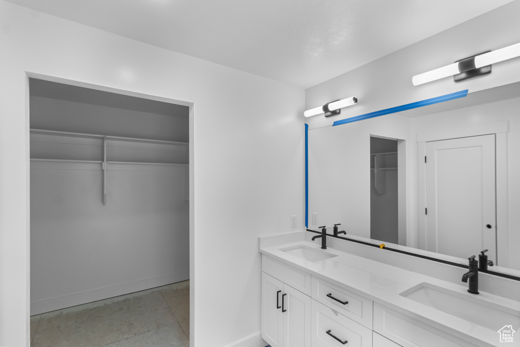 Bathroom with double vanity, a spacious closet, baseboards, and a sink