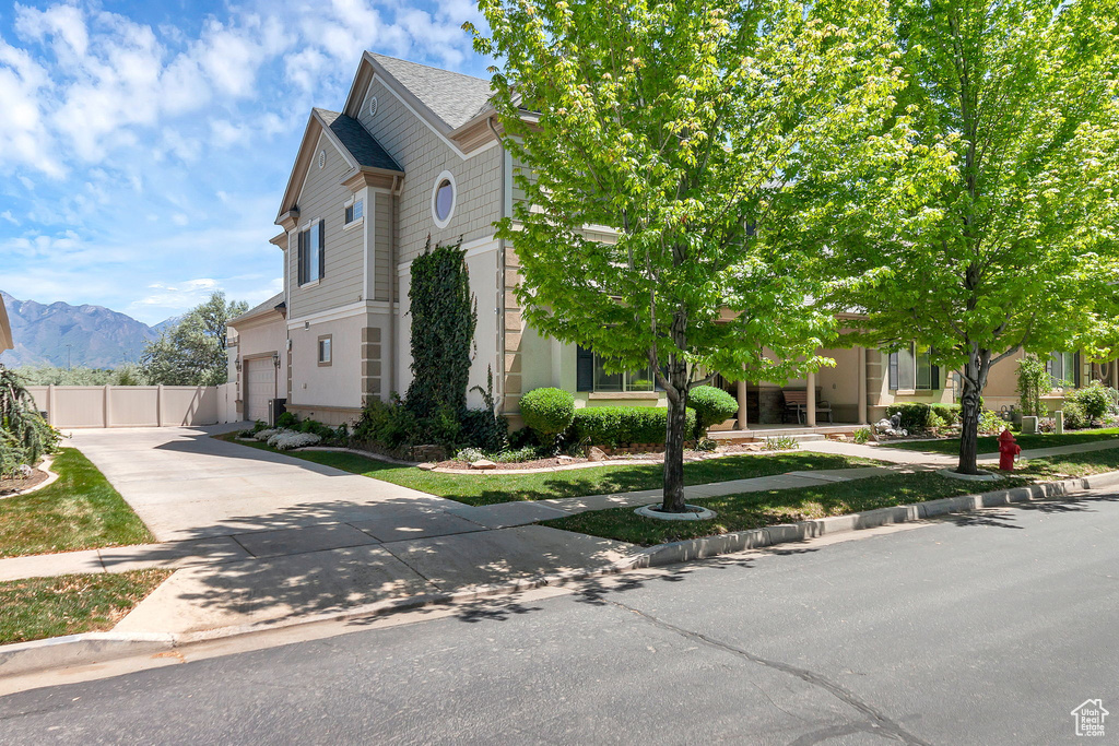 View of front of property featuring driveway, a mountain view, a garage, and fence