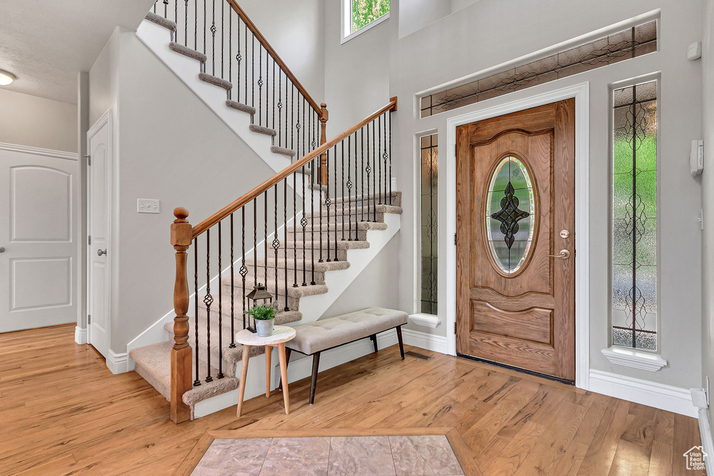 Foyer with wood finished floors, baseboards, stairway, and a towering ceiling