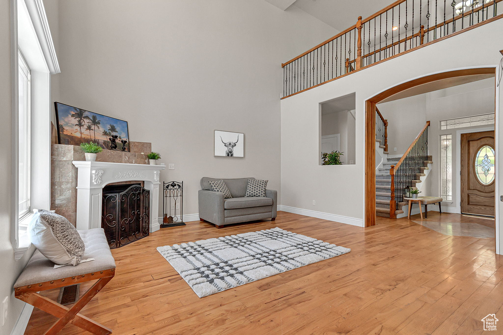 Living room with a high ceiling, wood finished floors, baseboards, stairway, and a fireplace