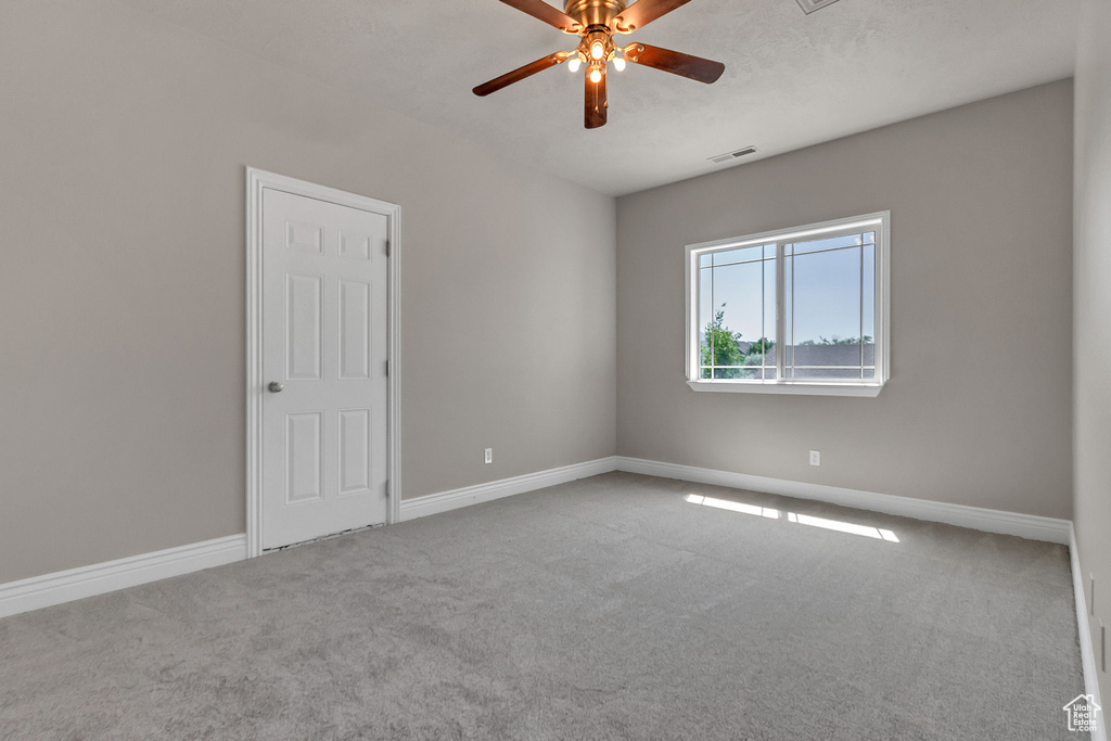 Empty room with ceiling fan, carpet, and baseboards