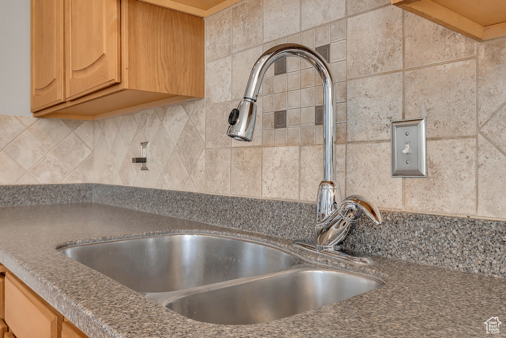 Detailed view of a sink, tasteful backsplash, and dark countertops