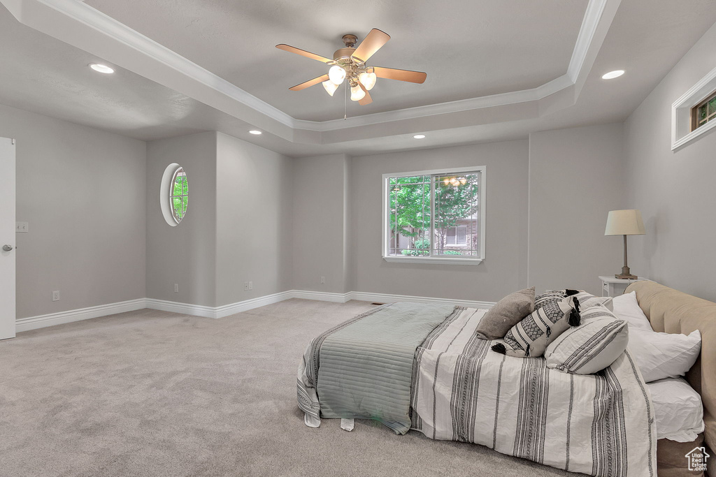 Bedroom featuring crown molding, a tray ceiling, multiple windows, light carpet, and recessed lighting