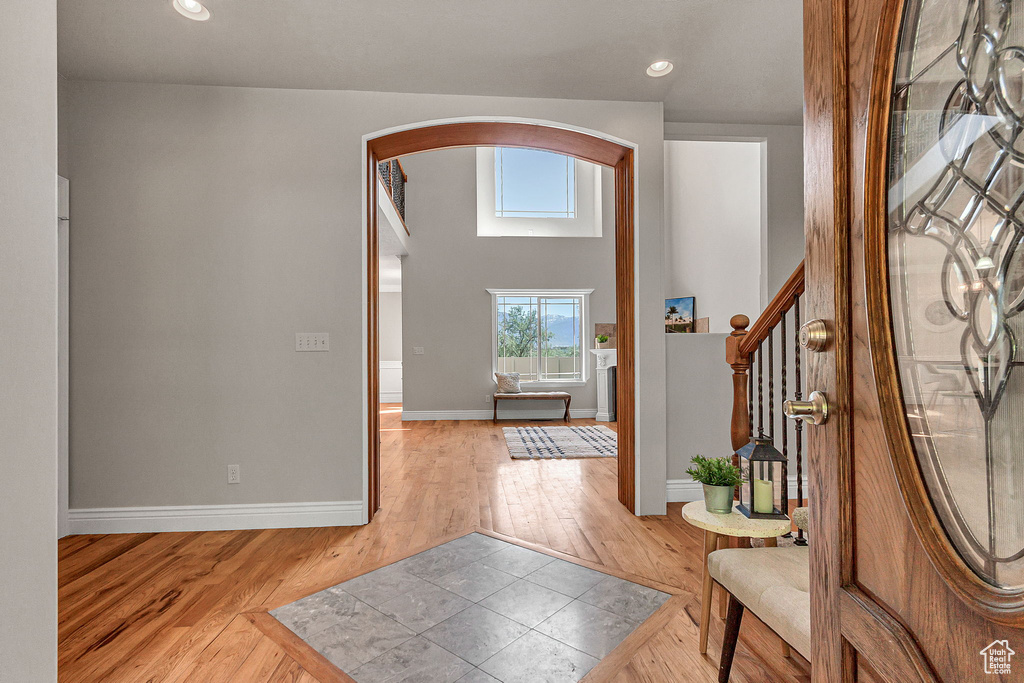 Entryway featuring arched walkways, light wood finished floors, stairway, baseboards, and recessed lighting