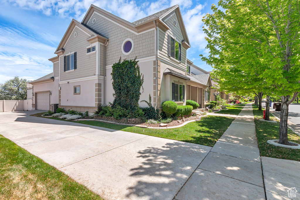 View of side of home featuring an attached garage, driveway, and stucco siding