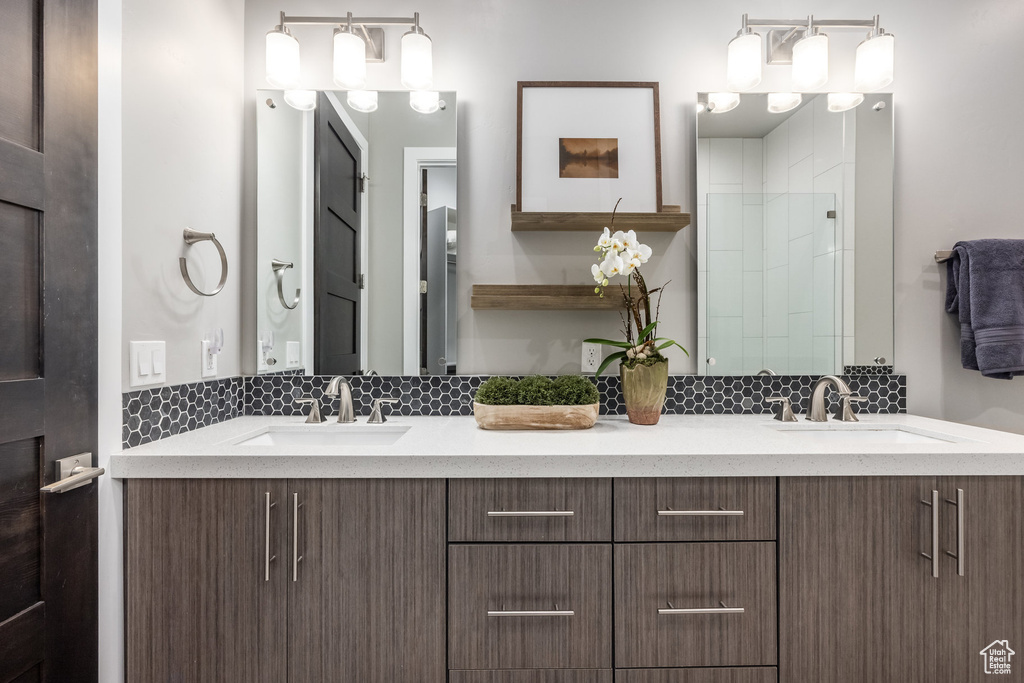 Bathroom with double vanity, decorative backsplash, and a sink