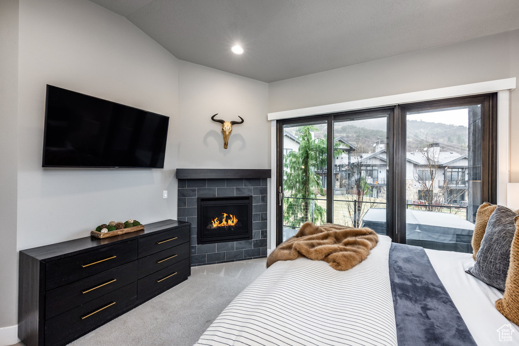 Bedroom featuring access to exterior, vaulted ceiling, carpet, and a fireplace