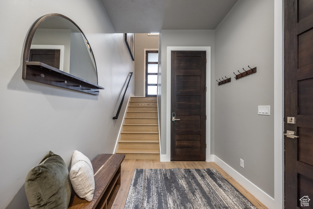 Entrance foyer featuring light wood finished floors, stairway, and baseboards