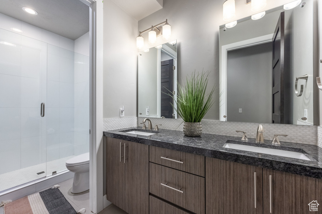 Bathroom with toilet, double vanity, a sink, and a shower stall