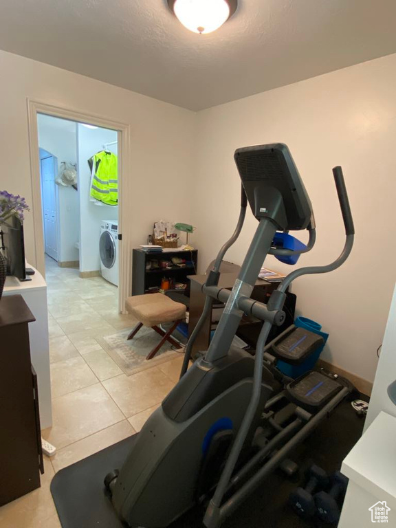 Workout area with light tile patterned floors and washer / dryer