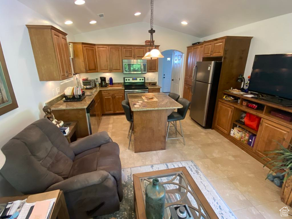 Kitchen featuring stainless steel appliances, a breakfast bar, open floor plan, arched walkways, and lofted ceiling