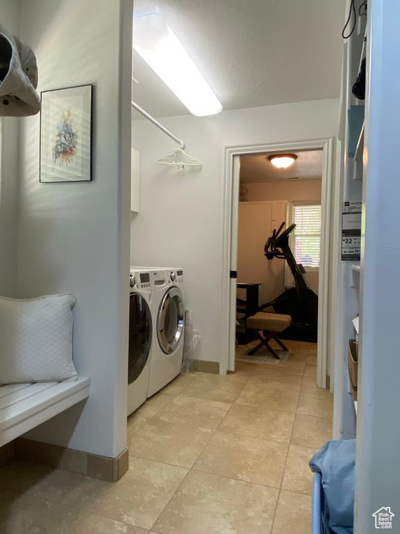 Laundry area with baseboards, light tile patterned floors, washing machine and clothes dryer, and laundry area