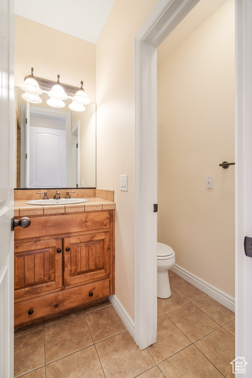 Bathroom with vanity, toilet, tile patterned flooring, and baseboards