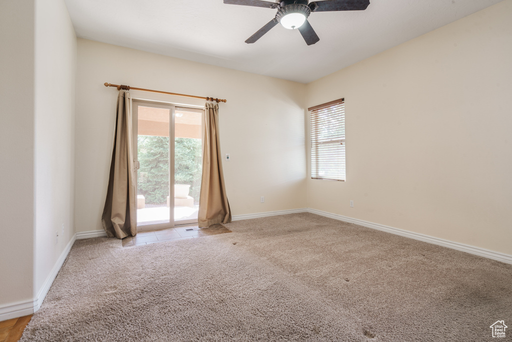 Empty room with a ceiling fan, light colored carpet, and baseboards