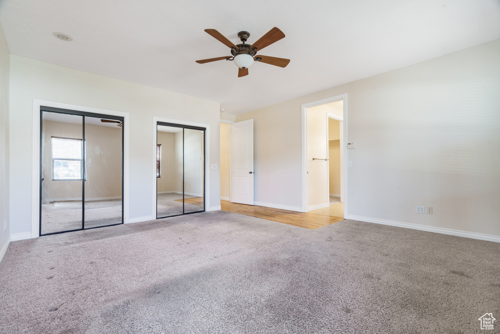 Unfurnished bedroom with a ceiling fan, two closets, carpet floors, and baseboards