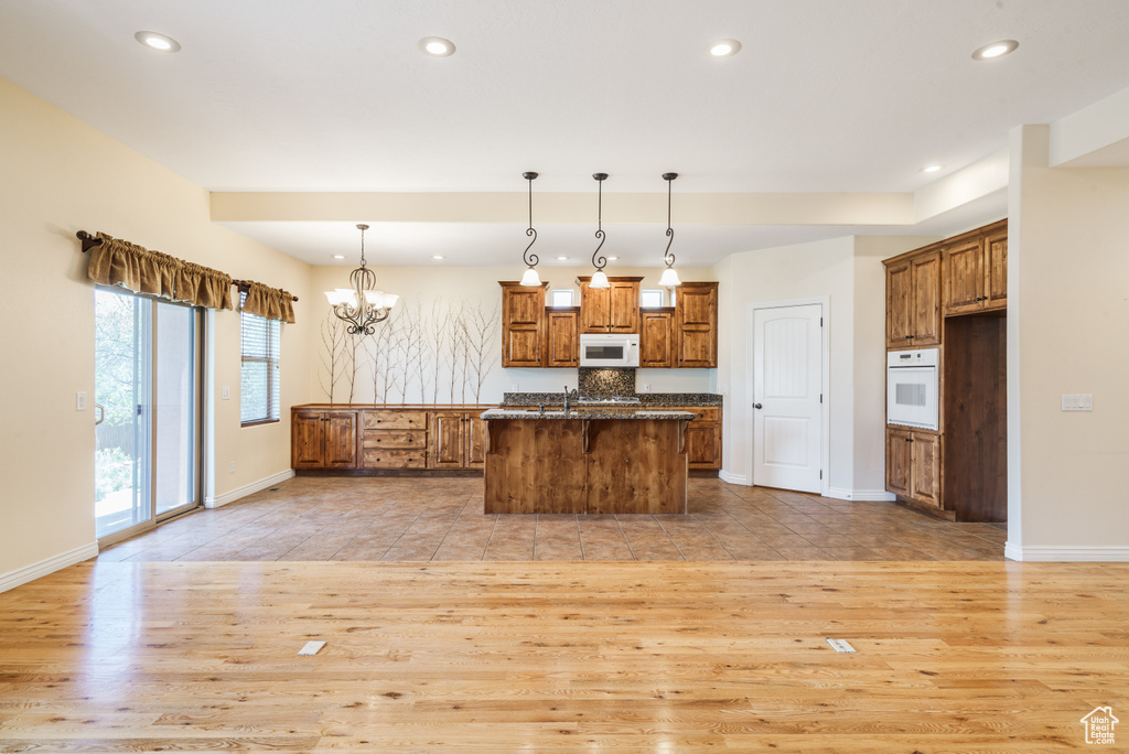 Kitchen with light wood-style flooring, brown cabinetry, and white appliances