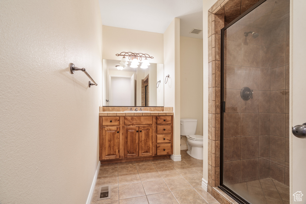 Bathroom with tile patterned floors, vanity, toilet, and a stall shower
