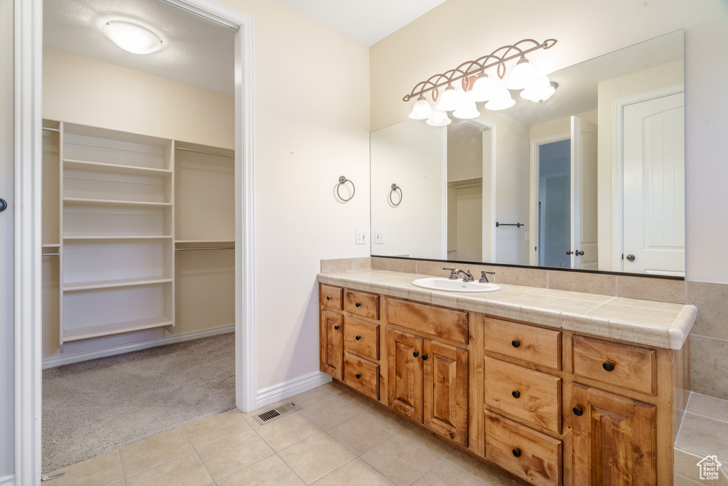 Bathroom with a walk in closet, tile patterned flooring, visible vents, and vanity