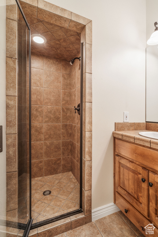Bathroom with tile patterned floors, vanity, a shower stall, and baseboards
