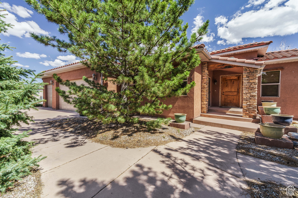 View of front facade featuring a garage, stucco siding, and a tiled roof