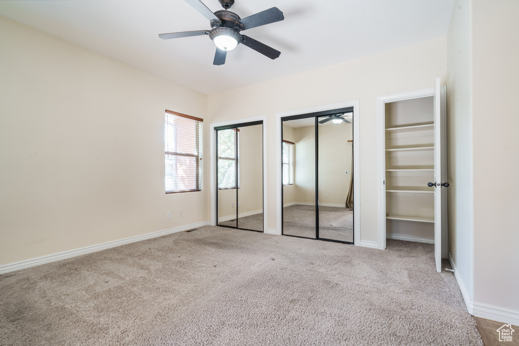 Unfurnished bedroom featuring two closets, carpet flooring, and multiple windows
