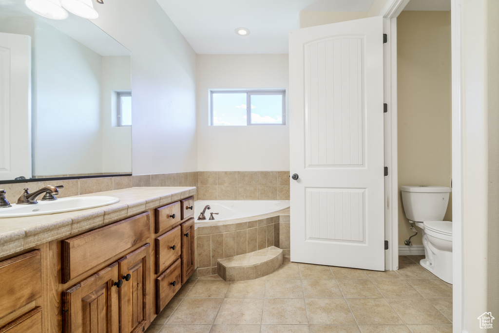 Full bath with tile patterned floors, vanity, toilet, and a bath
