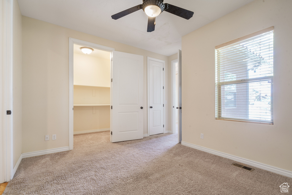 Unfurnished bedroom featuring baseboards, visible vents, a walk in closet, and carpet