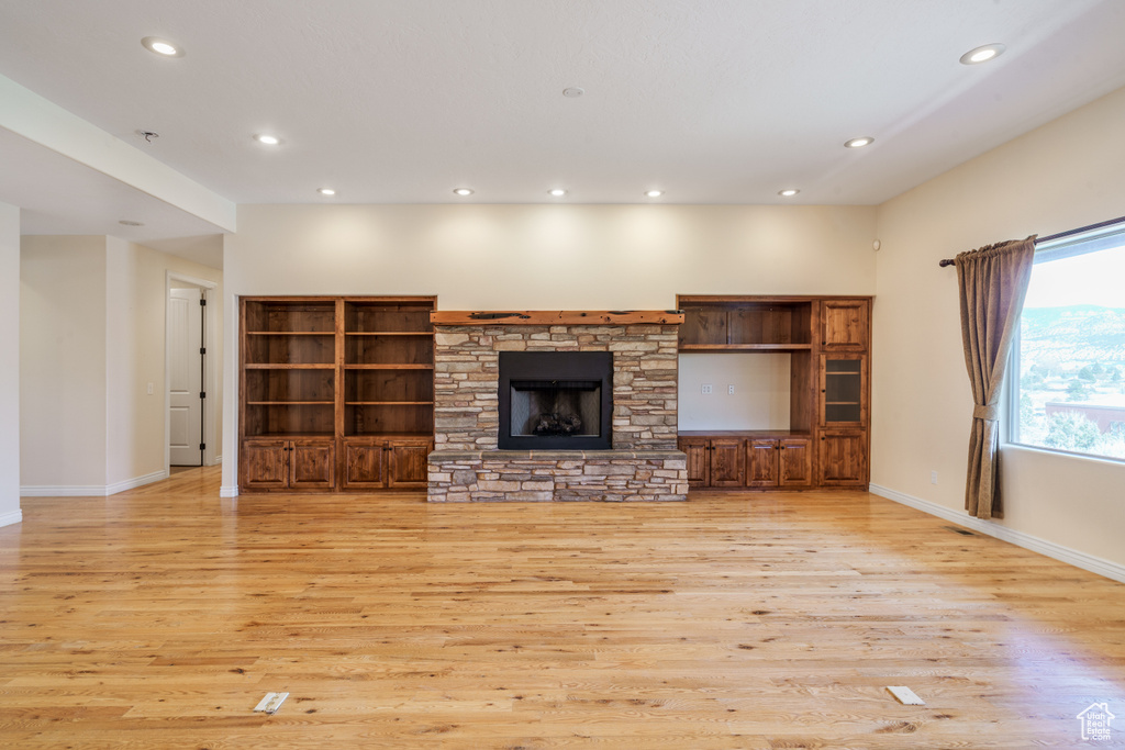 Unfurnished living room featuring baseboards, recessed lighting, light wood-style floors, and a fireplace