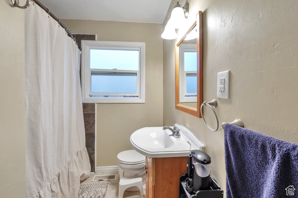 Bathroom with a shower with curtain, vanity, tile patterned floors, toilet, and baseboards
