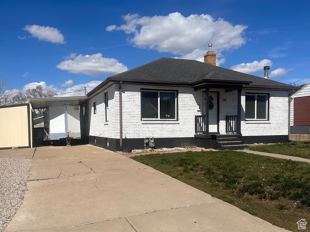 View of front of house with a chimney, brick siding, a front lawn, and concrete driveway