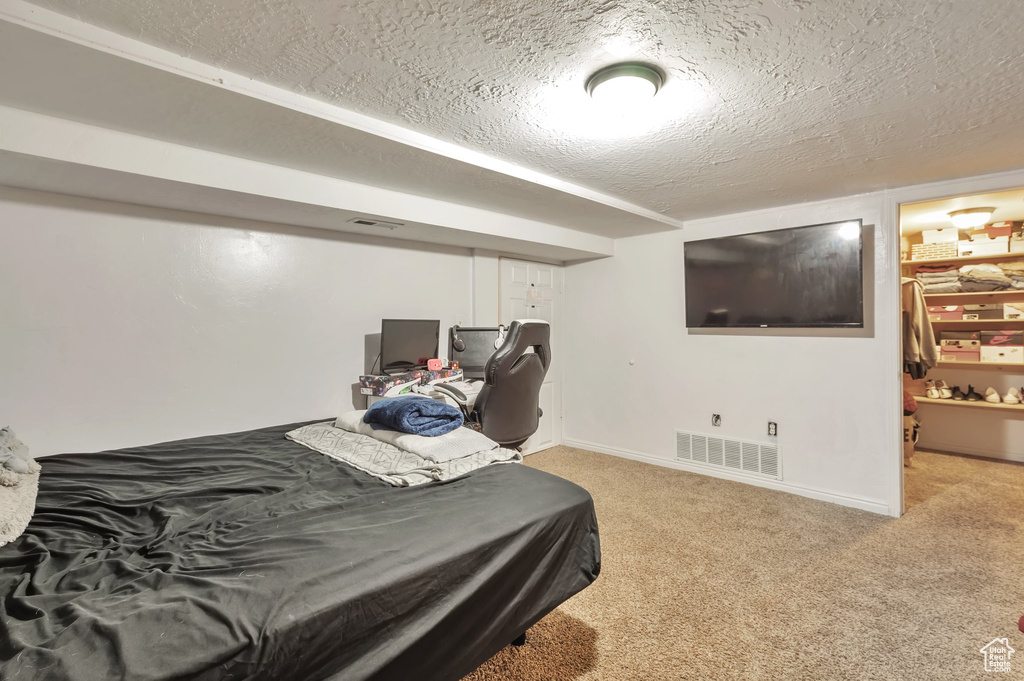 Bedroom featuring a textured ceiling, visible vents, light colored carpet, and baseboards