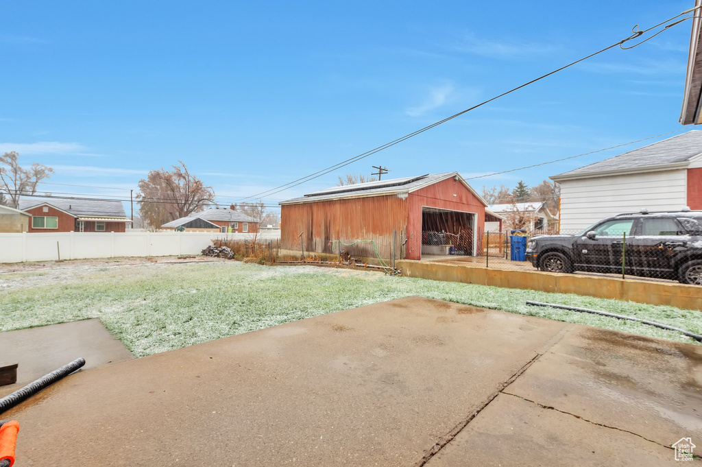 View of yard with a detached garage, fence, and an outbuilding