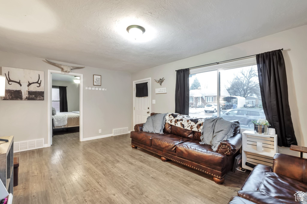 Living area featuring a textured ceiling, visible vents, wood finished floors, and baseboards