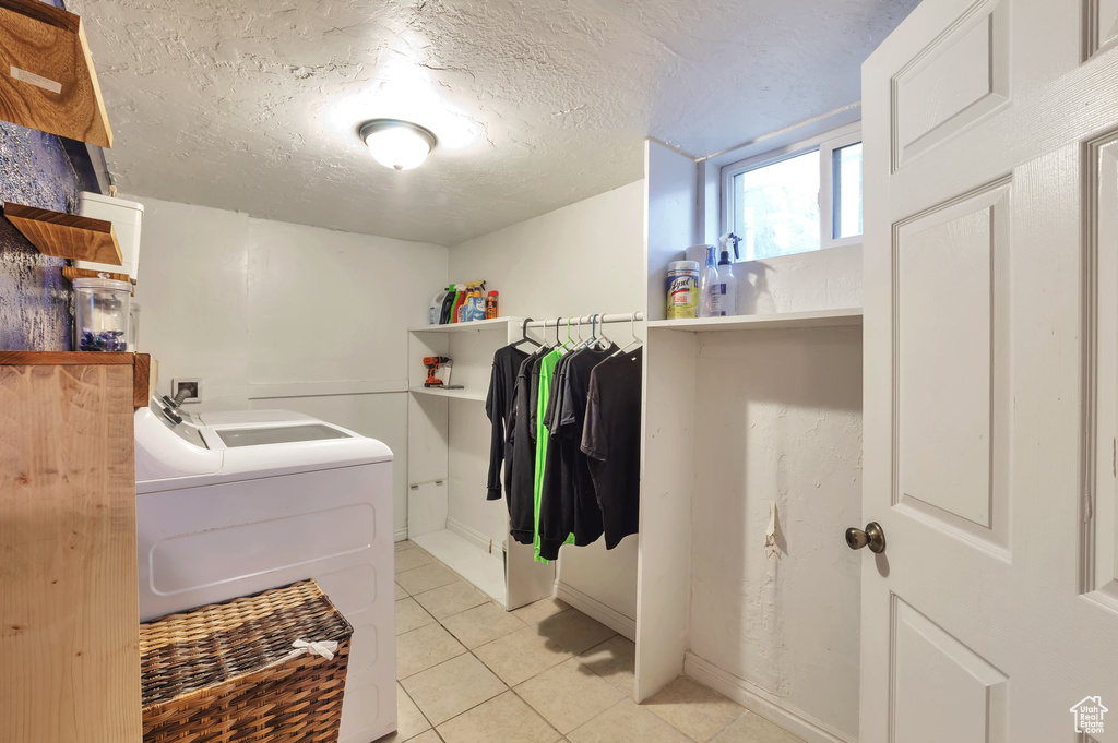 Laundry area featuring light tile patterned floors, independent washer and dryer, laundry area, and baseboards