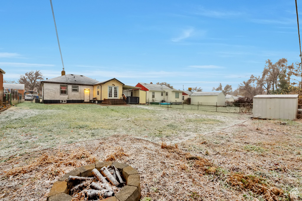 View of yard featuring a storage unit, an outdoor fire pit, an outbuilding, and a fenced backyard
