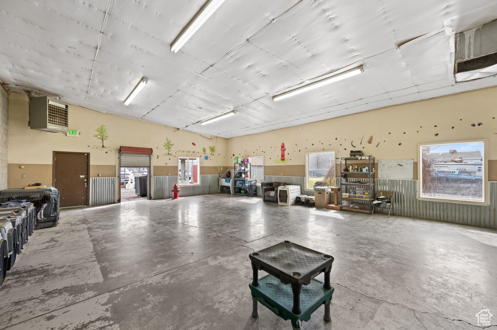 Miscellaneous room featuring concrete floors, a wainscoted wall, and lofted ceiling
