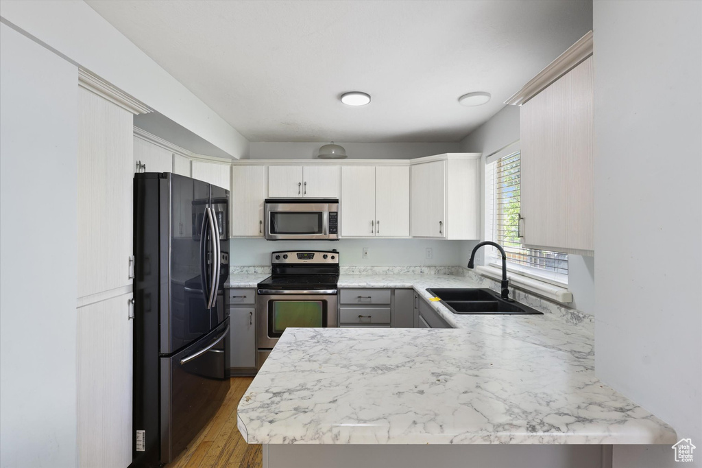Kitchen featuring stainless steel appliances, a peninsula, light countertops, and a sink