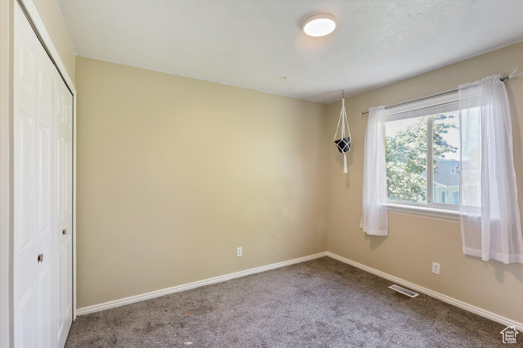 Unfurnished bedroom with carpet, visible vents, baseboards, and a closet