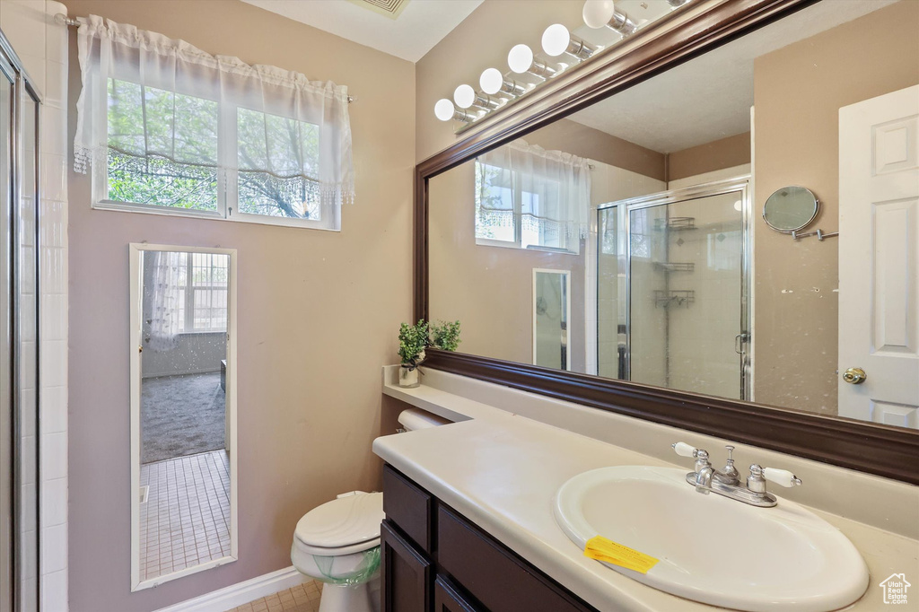 Full bathroom featuring toilet, a stall shower, vanity, and plenty of natural light