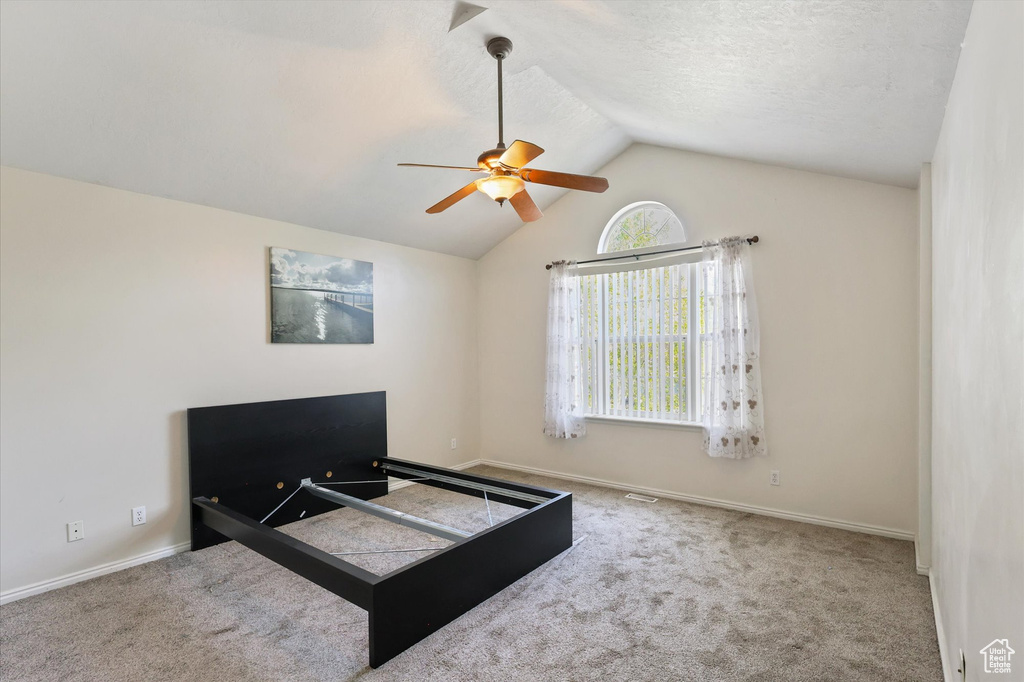 Carpeted bedroom featuring baseboards, visible vents, ceiling fan, and lofted ceiling