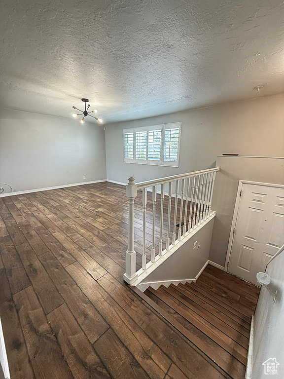 Unfurnished room featuring a chandelier, hardwood / wood-style floors, and a textured ceiling