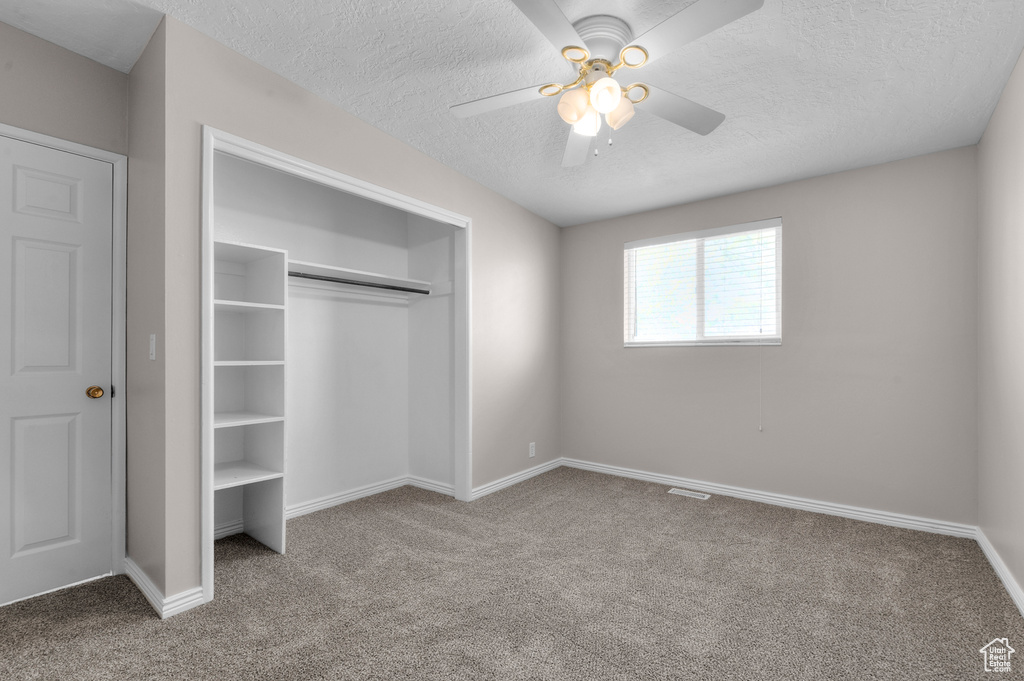 Unfurnished bedroom with a textured ceiling, a closet, baseboards, and carpet floors