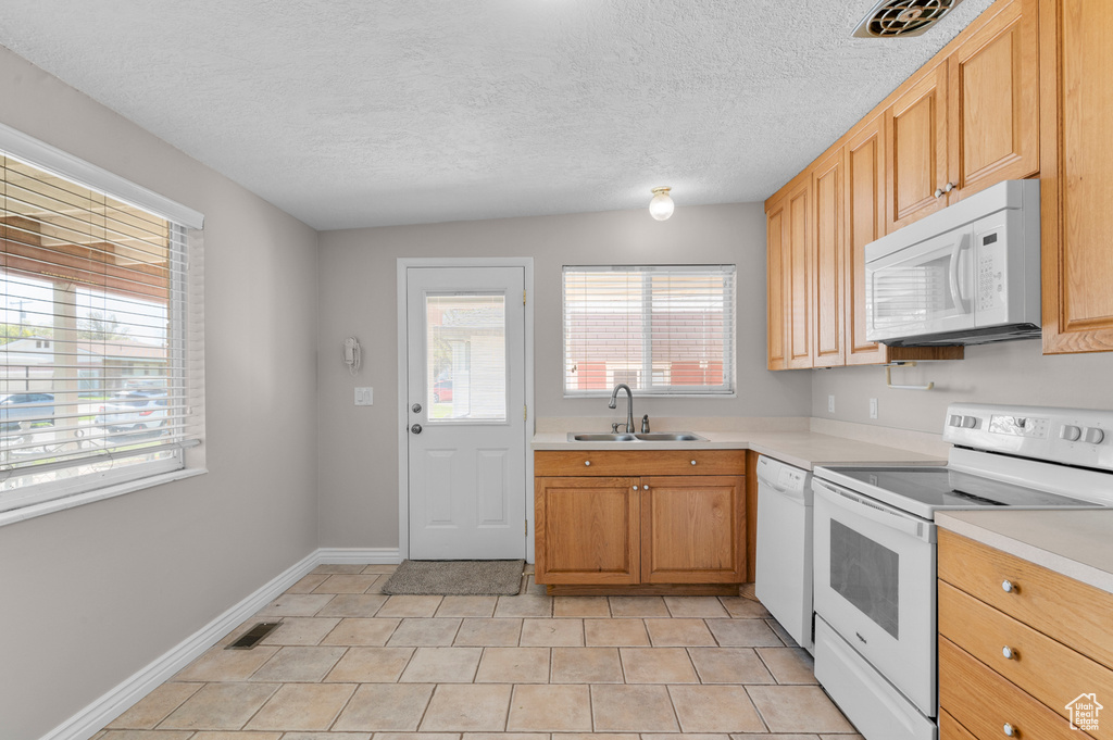 Kitchen featuring a wealth of natural light, visible vents, white appliances, and a sink