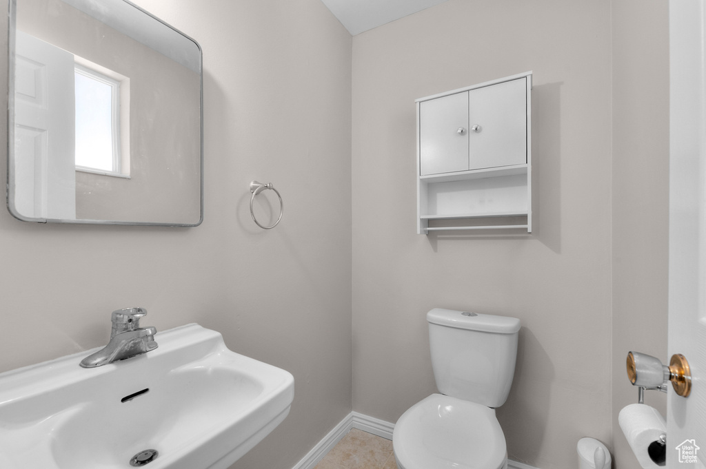 Bathroom featuring toilet, a sink, and baseboards