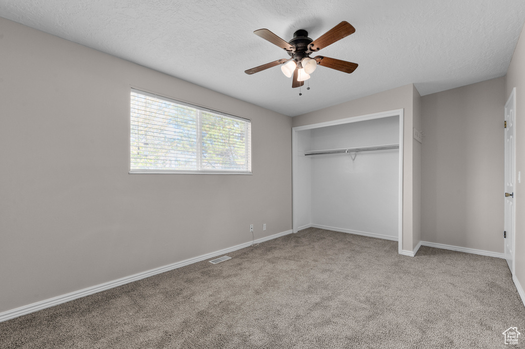 Unfurnished bedroom featuring a closet, carpet flooring, baseboards, visible vents, and a textured ceiling