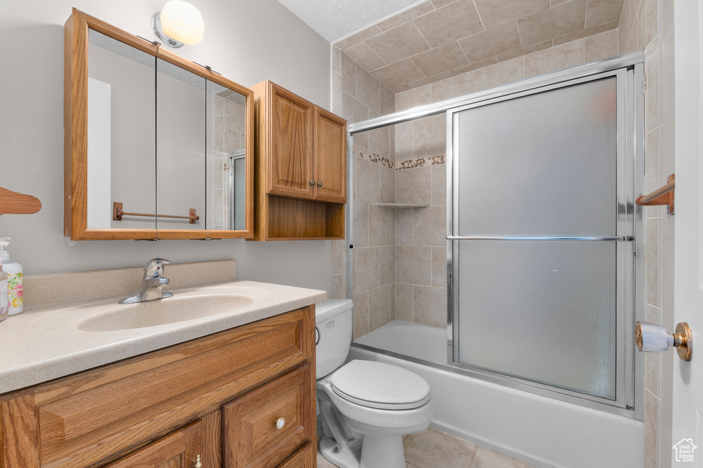 Full bathroom with enclosed tub / shower combo, tile patterned floors, toilet, and vanity