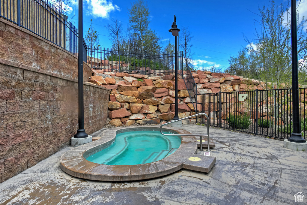 View of pool featuring fence and an in ground hot tub