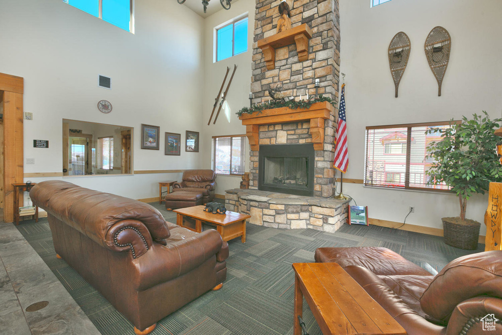 Living area with a towering ceiling, visible vents, a stone fireplace, and baseboards