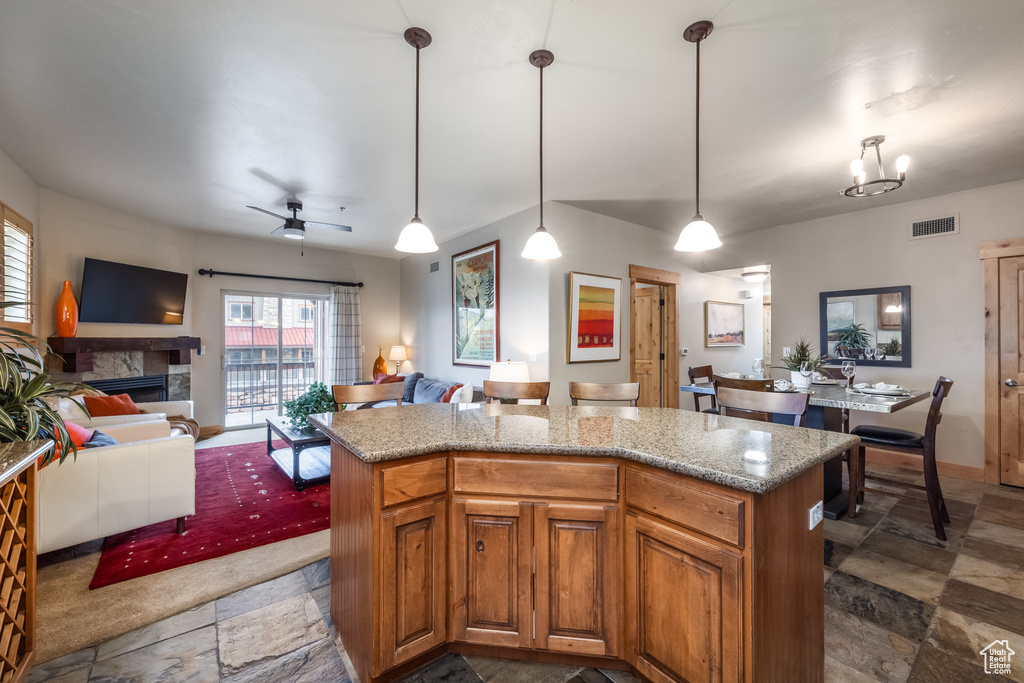 Kitchen with visible vents, a fireplace, stone tile flooring, and open floor plan