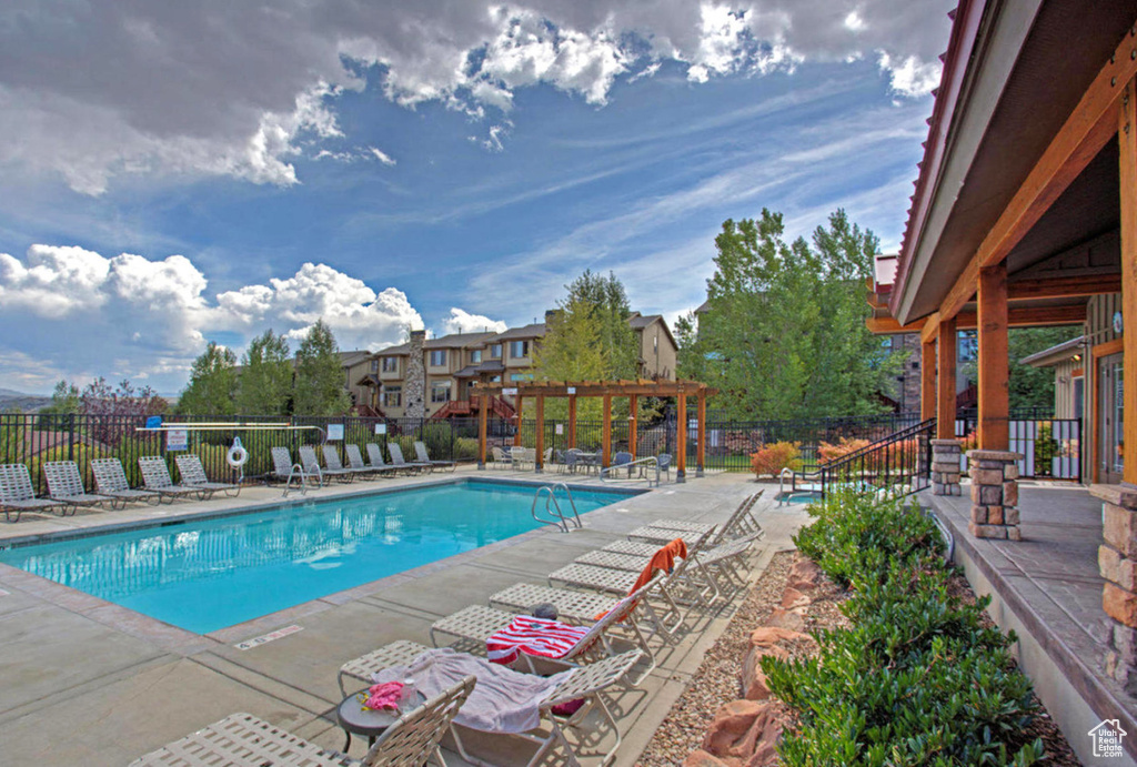 Pool with a pergola, a patio area, and fence